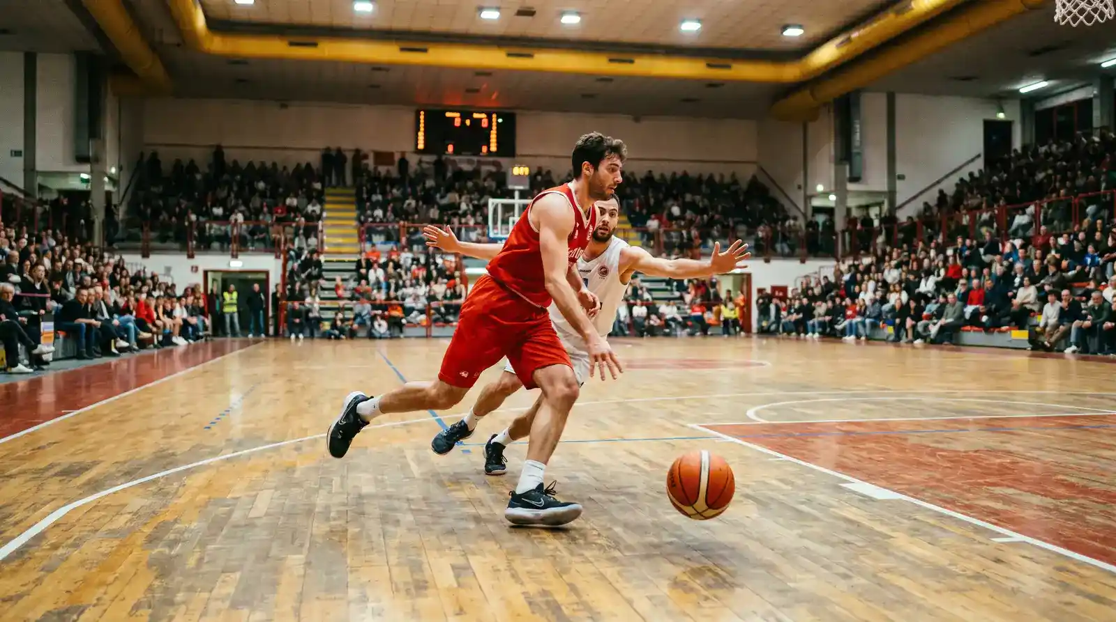 Azione di gioco in un palazzetto di pallacanestro italiano con due squadre a confronto sul parquet